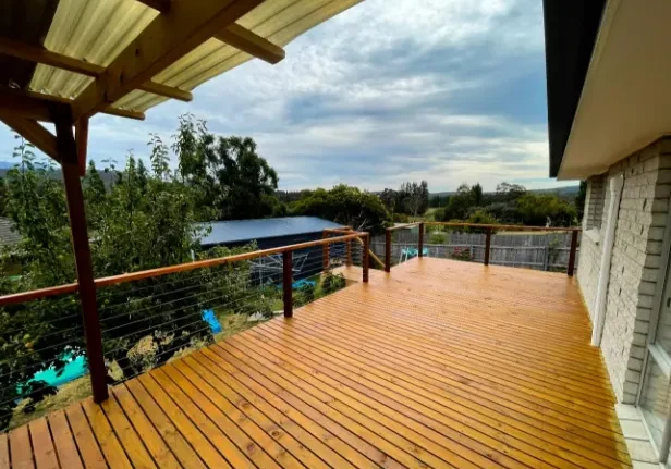 Wooden deck with wire balustrading and a polished handrail in Hobart TAS overlooking the garden area.